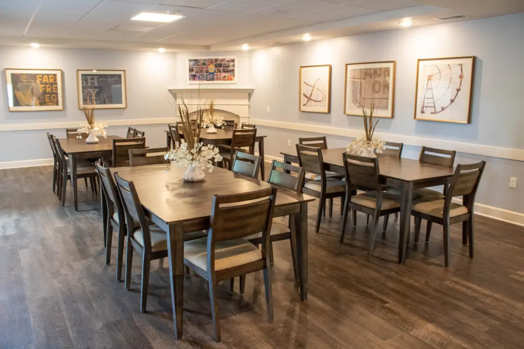 Conference-style dining room with dark wood tables and chairs, light blue walls, and framed prints along the wall.