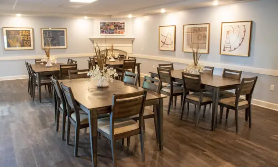 Conference-style dining room with dark wood tables and chairs, light blue walls, and framed prints along the wall.