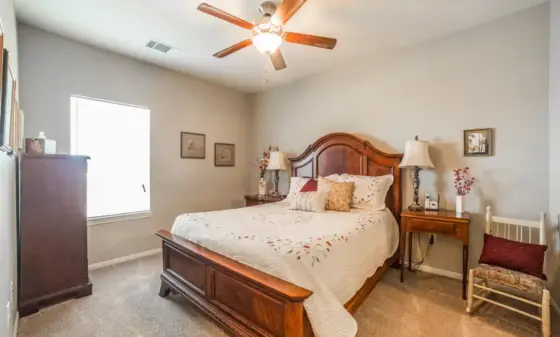 Bedroom with a dark wooden king-size bed, matching nightstands, and a ceiling fan with wooden blades."